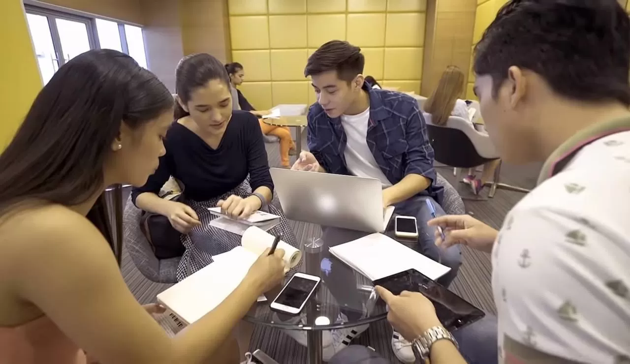 a group of young people sitting around a table with their gadgets