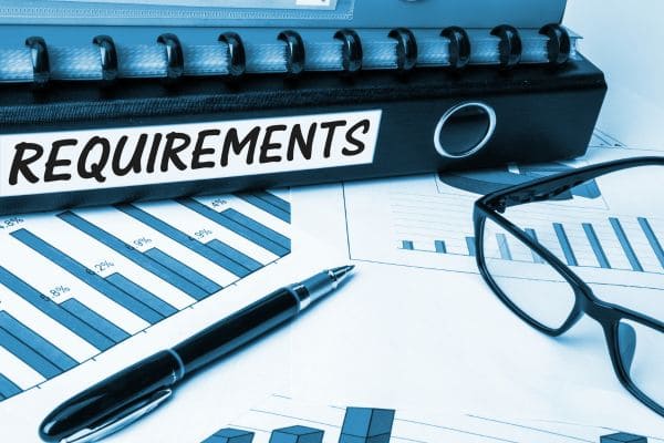 Binder labeled requirements with charts and glasses
