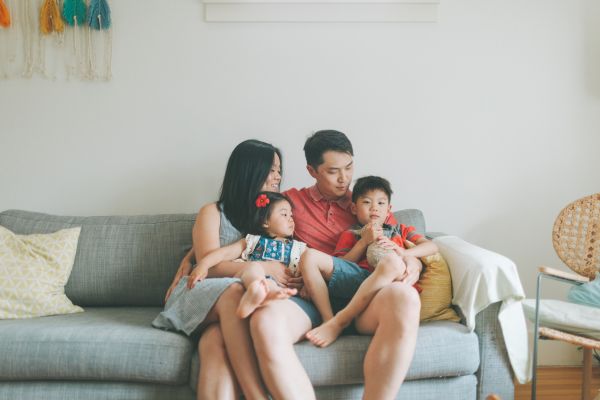 Family sitting together on a gray couch at home