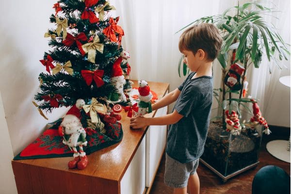 Child decorating small Christmas tree at home