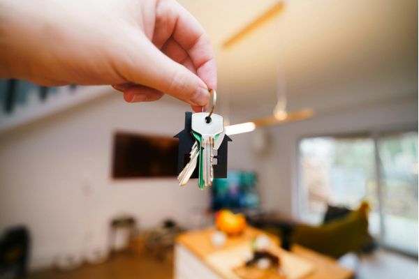 A hand holds a keyring with house-shaped charms, symbolizing a new home.